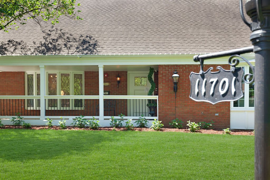 A brick house with a well-maintained lawn and a prominent address sign.