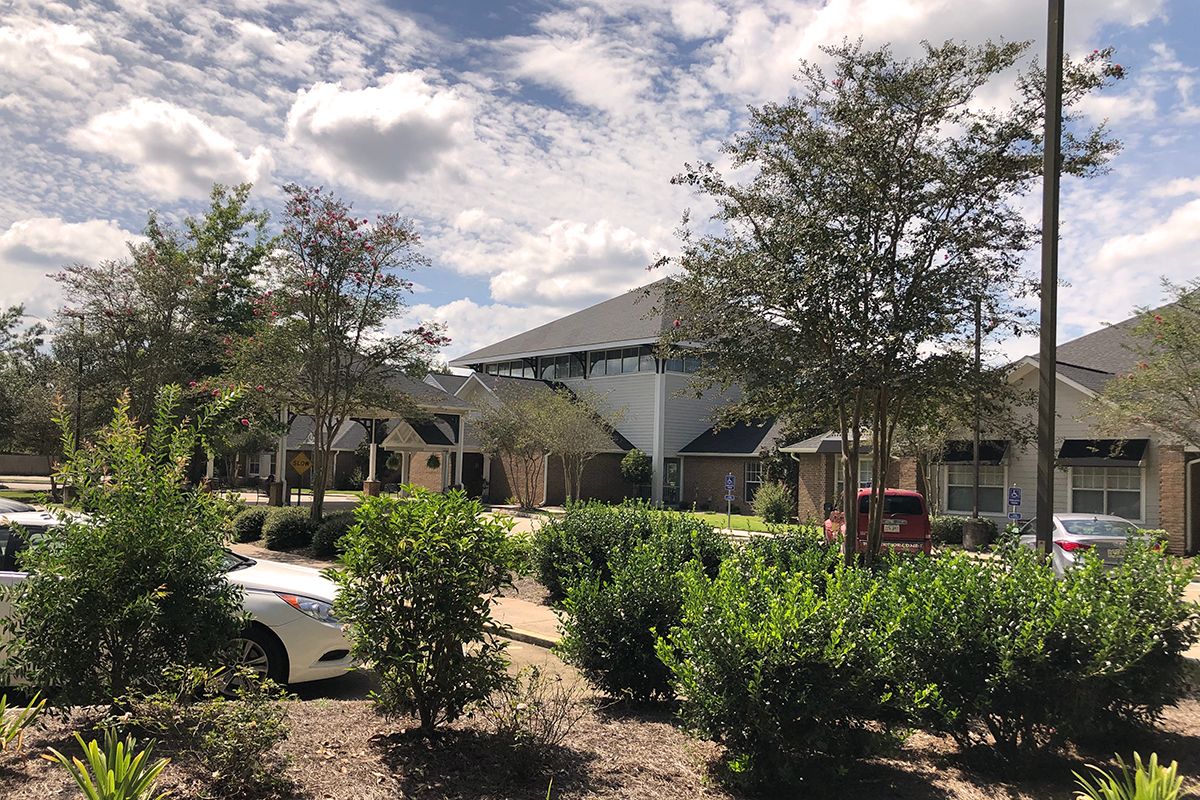 A suburban building surrounded by greenery under a cloudy sky.