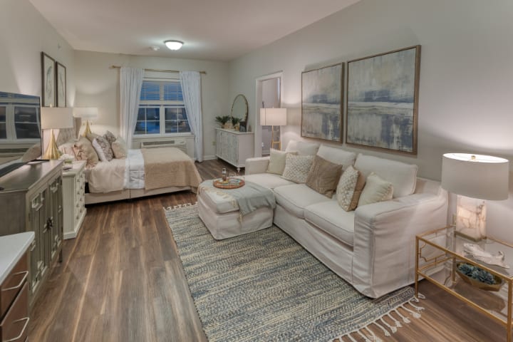 A modern open-concept living area featuring a cozy sofa, stylish decor, and a comfortable bed in the background.