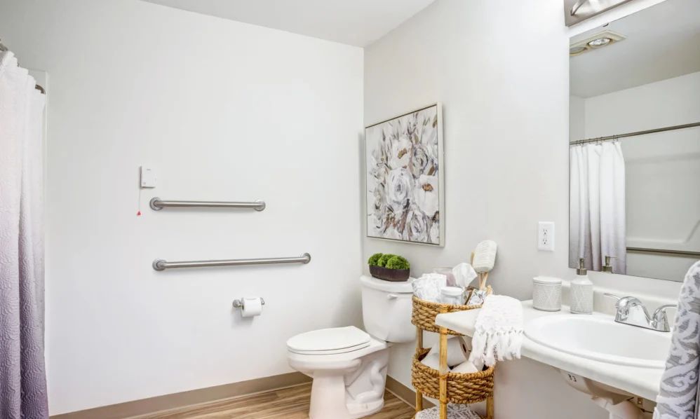 A modern bathroom featuring a toilet, decorative basket with towels, and sleek wall art.