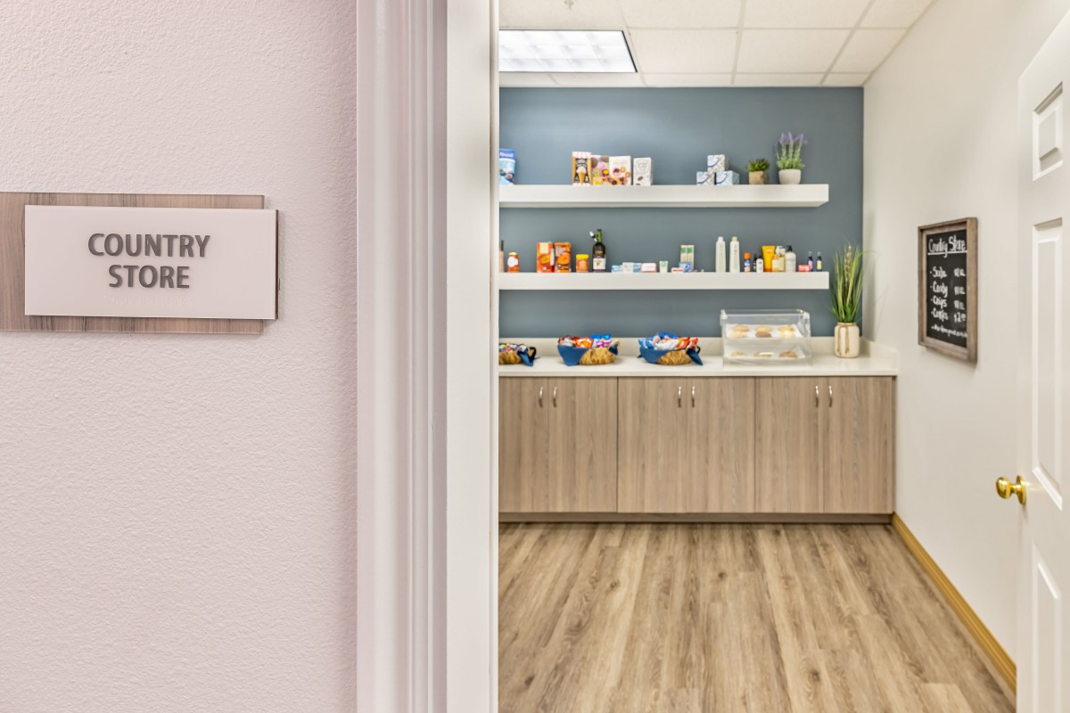 A modern office snack room with shelves stocked with snacks and beverages.