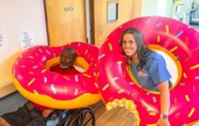Two people having fun with giant inflatable donut floats indoors.