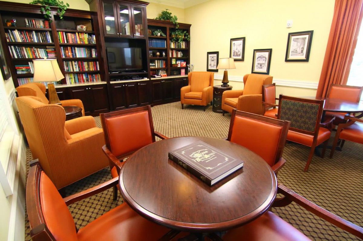 A cozy library room with comfortable seating and a television.