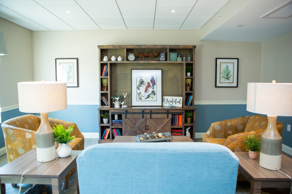 A cozy living room featuring a central bookshelf adorned with artwork and various decorative items.