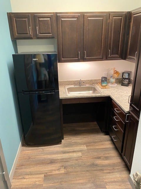 A modern kitchen with dark cabinets and a black refrigerator.