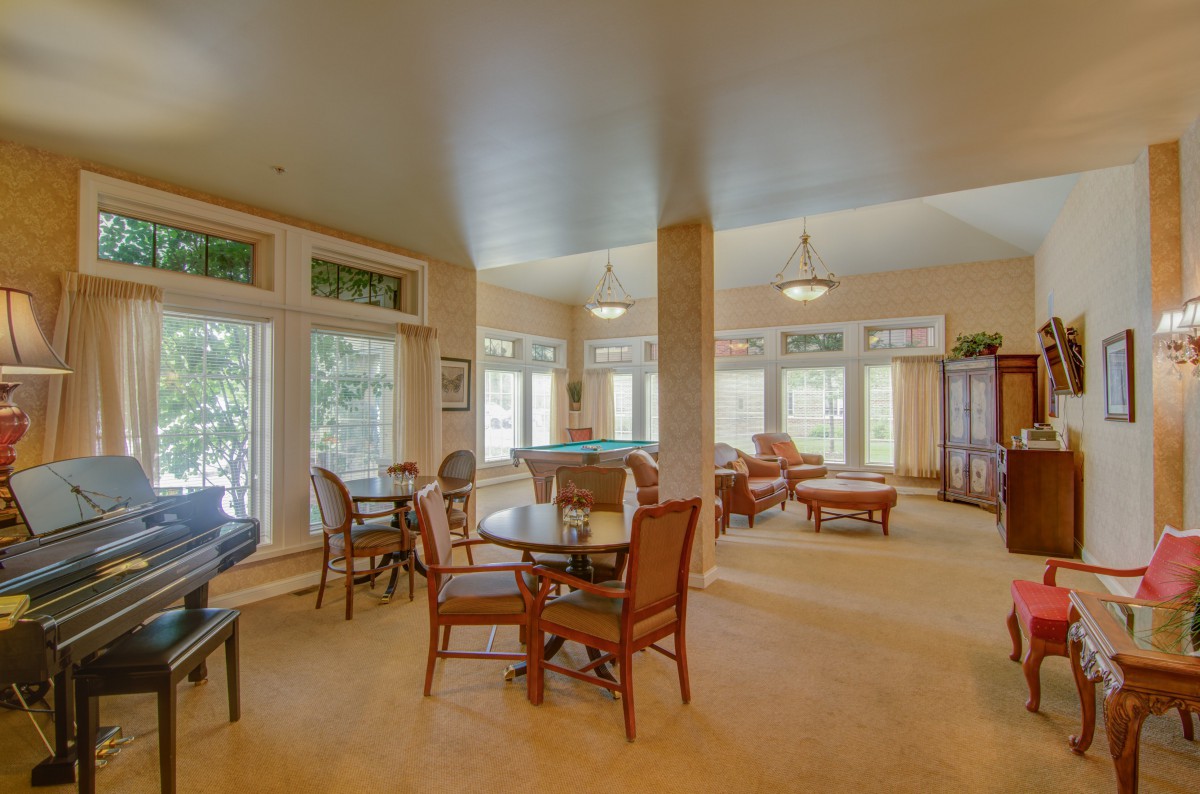 A spacious and well-lit living room with multiple seating areas, large windows, and elegant furniture.