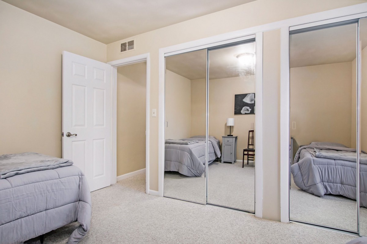 A bedroom with mirrored closet doors and neutral-colored decor.