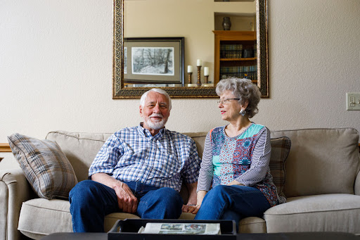 An elderly couple shares a joyful moment together in their cozy living room.