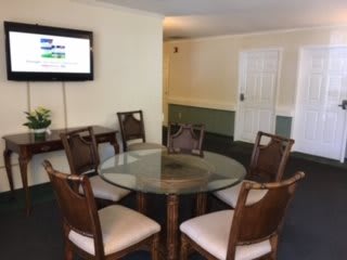 A simple dining or meeting area with a glass-top table and five chairs.