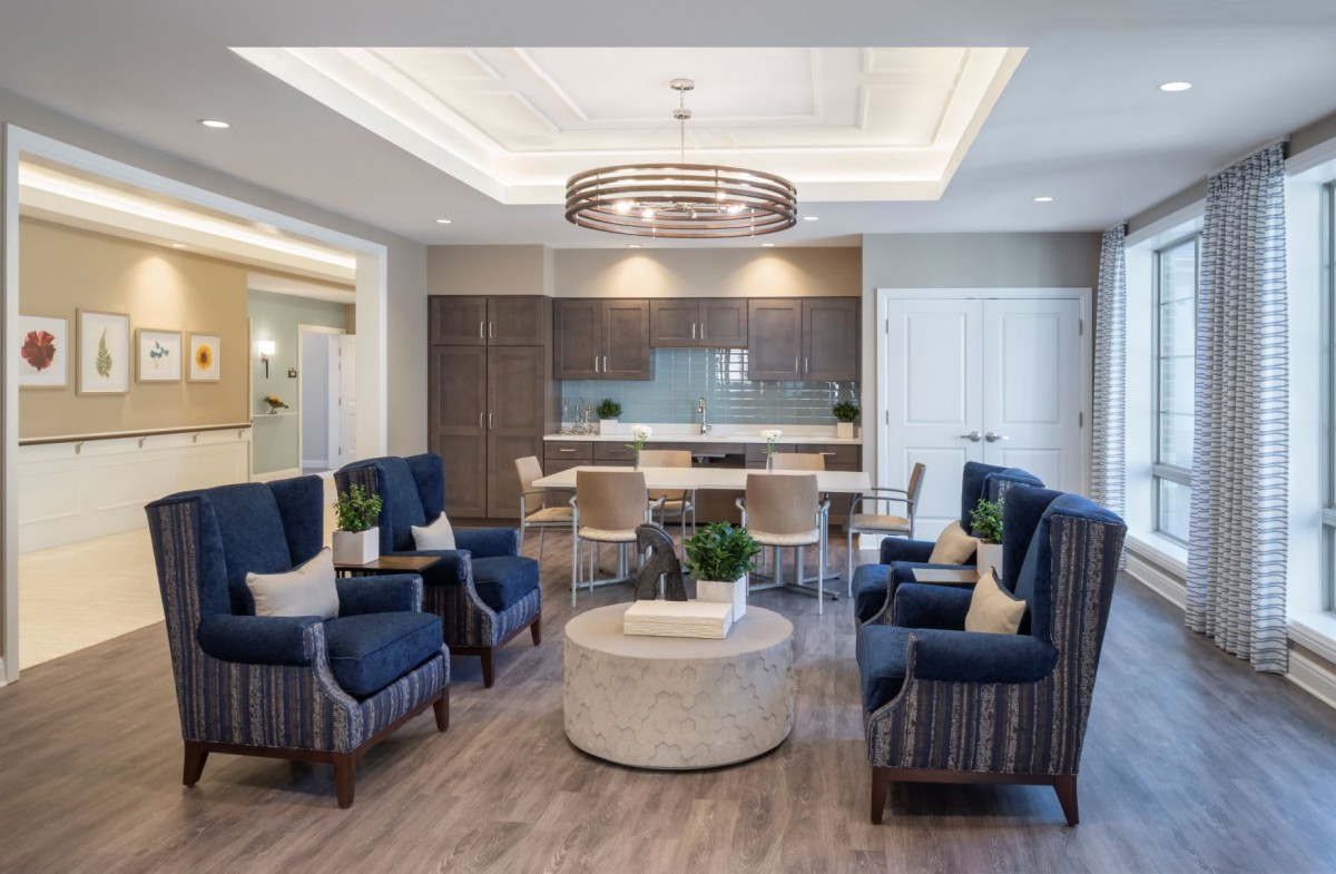 A modern living room with blue chairs, a marble coffee table, and stylish lighting.
