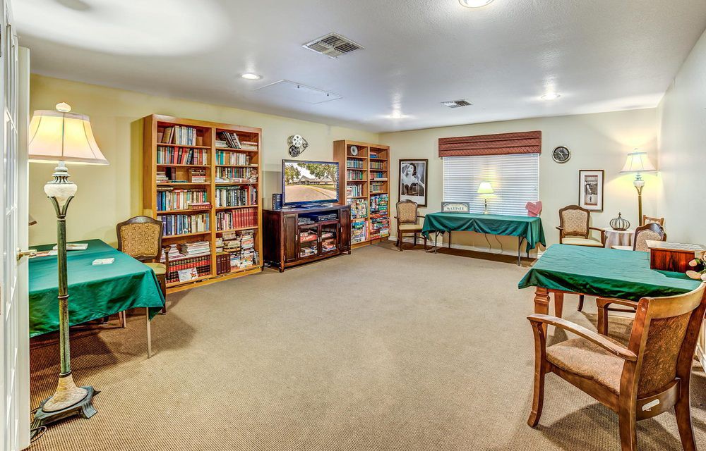 A cozy library room with bookshelves, tables, and chairs for reading.