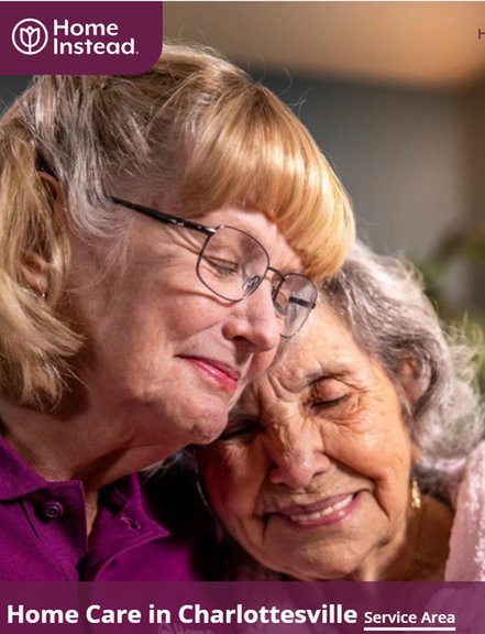 Two elderly women share a warm, affectionate moment, leaning their heads together and smiling.