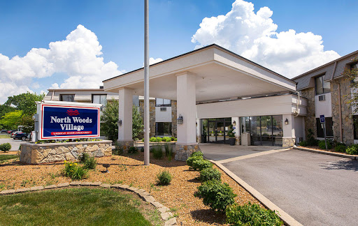 Entrance to a hospitality facility surrounded by landscaped gardens under a sunny sky.
