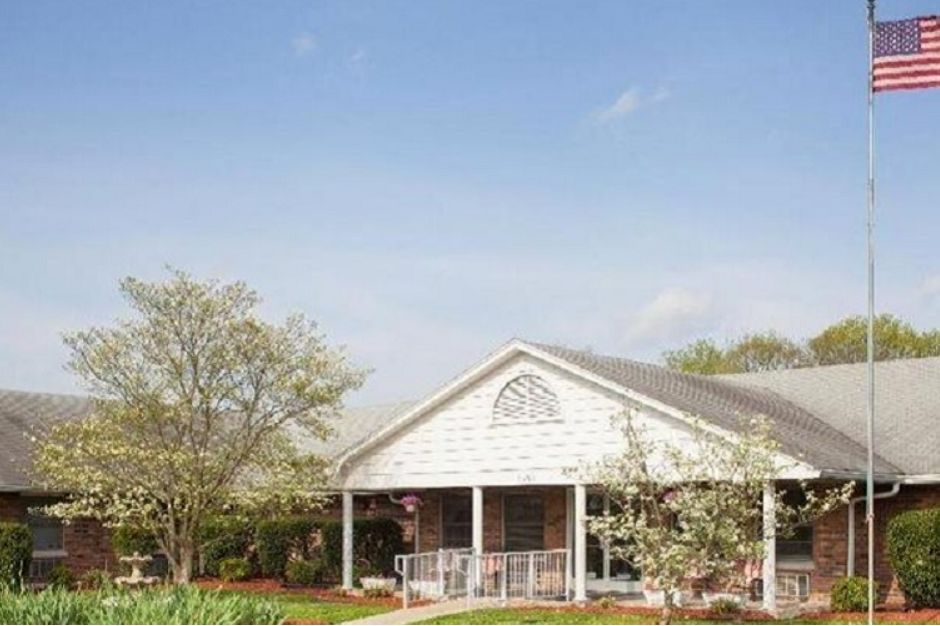 A charming house with a front porch surrounded by trees under a clear blue sky.