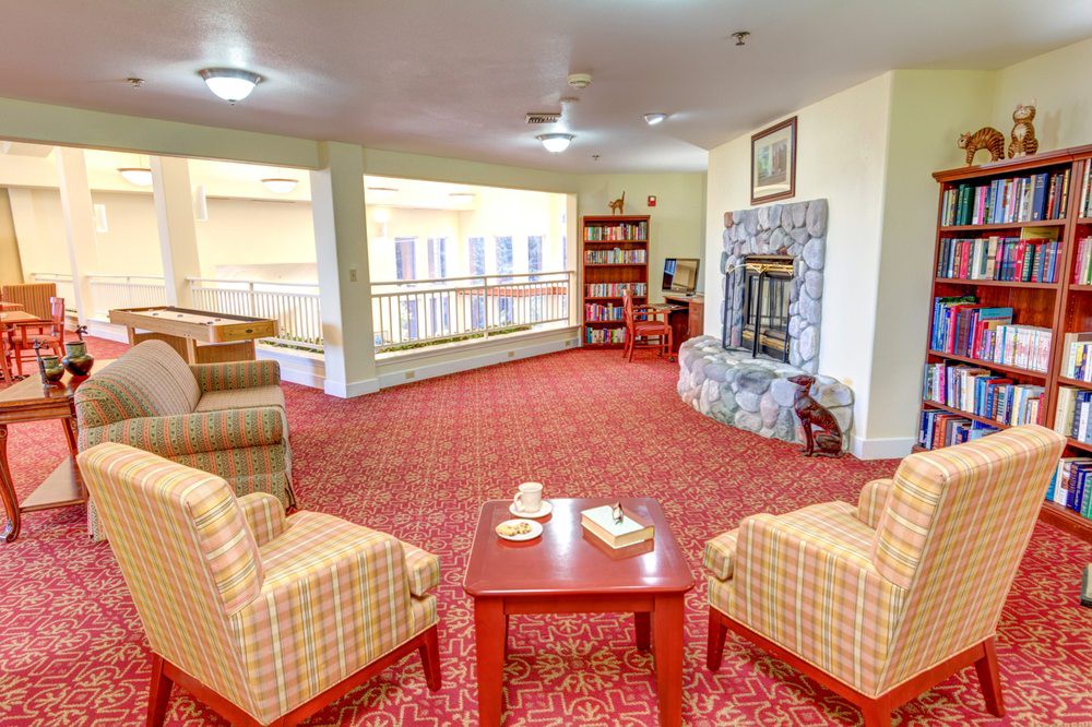 A cozy living room with comfortable seating, a stone fireplace, and a bookshelf.