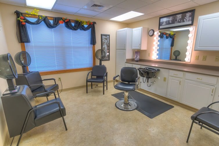 A cozy and well-lit hair salon interior featuring a barber chair, mirrors, and a small waiting area.