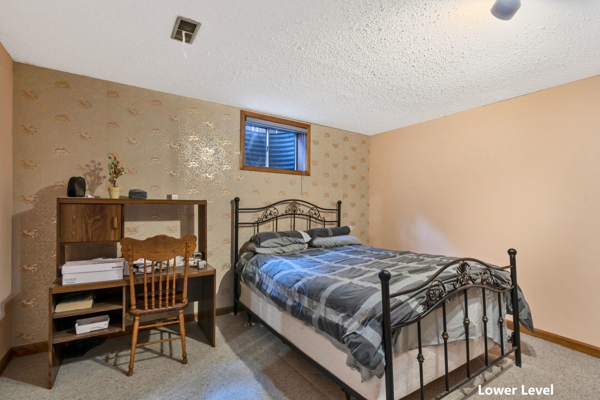 A cozy bedroom with a metal-framed bed, a desk, and a small window.