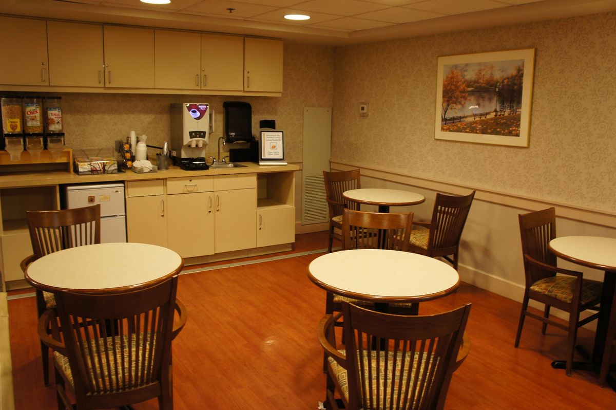 A cozy break room with tables, chairs, and a kitchenette equipped with a coffee machine.