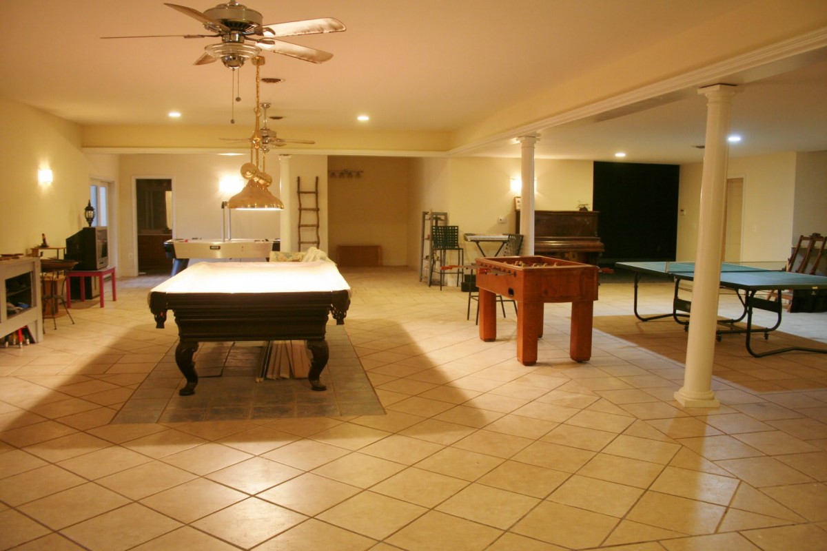 A spacious game room featuring a billiards table, foosball table, and ping pong table.