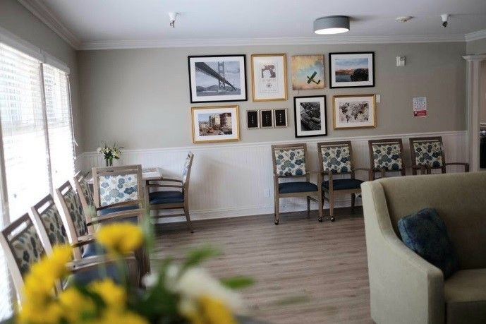 A cozy seating area with framed artwork on the wall and a table with chairs, accented by fresh flowers.