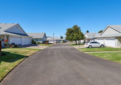 A quiet suburban neighborhood street lined with modern homes and parked cars.