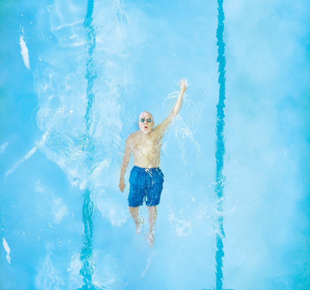 A person swimming in a clear blue pool, enjoying an outdoor exercise.