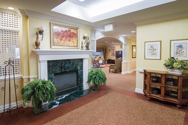 A cozy and elegant living room with a fireplace, artwork, and plush carpeting.