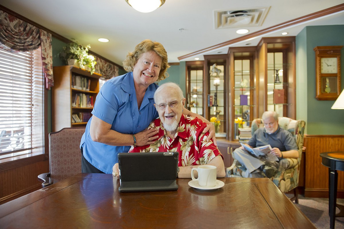 An elderly couple enjoying time together with a tablet in a cozy library setting.
