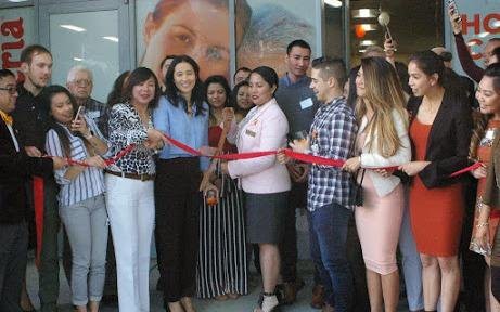 A group of people at a ribbon-cutting ceremony celebrating a new business opening.