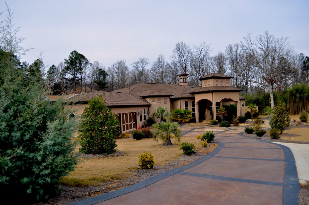 A large house with a landscaped driveway surrounded by trees.