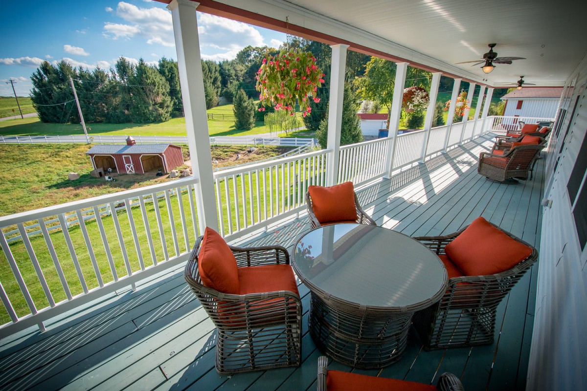 A spacious porch with comfortable seating overlooks a scenic countryside landscape.