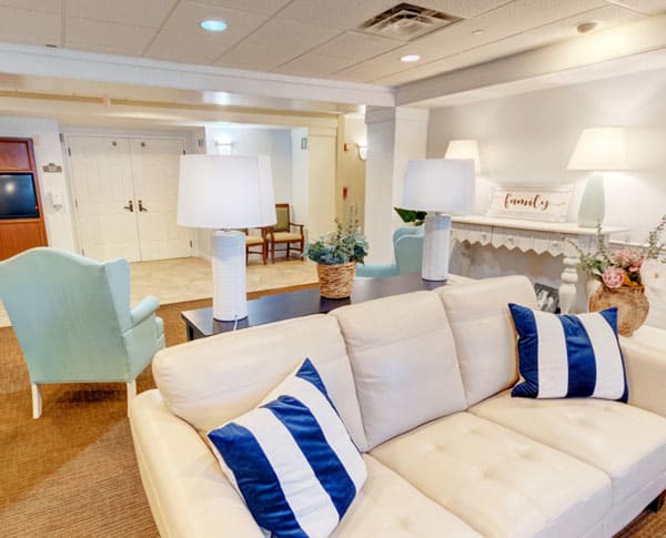 A modern living room featuring a cream sofa with blue and white pillows, complemented by elegant lamps and stylish decor.