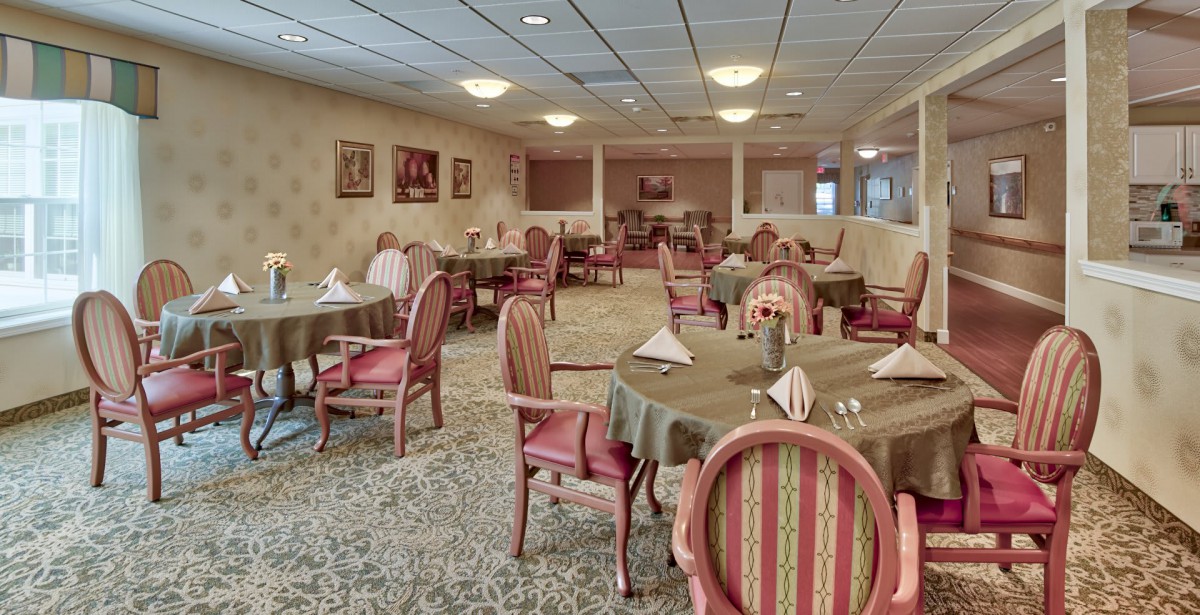 A formal dining room with elegantly set tables and upholstered chairs.