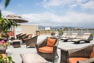 A rooftop patio with wicker chairs and umbrellas on a sunny day.