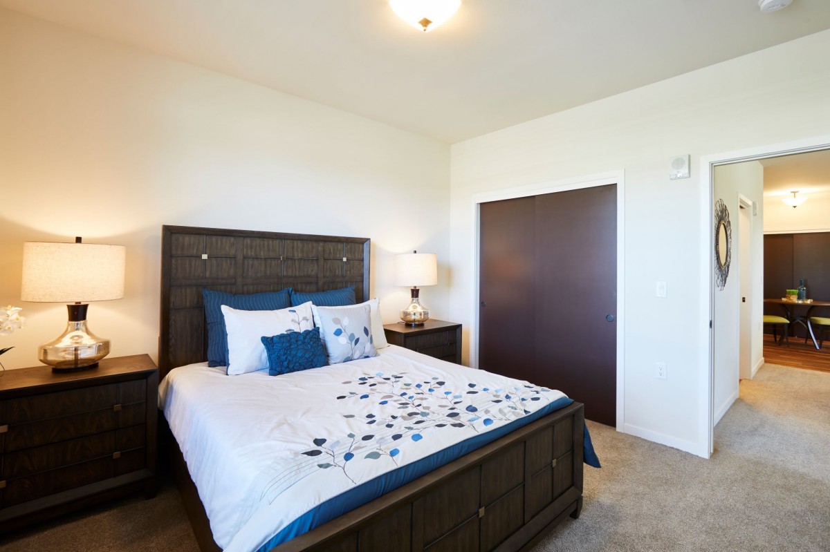 A neatly organized bedroom with a large bed, nightstand, and lamp.