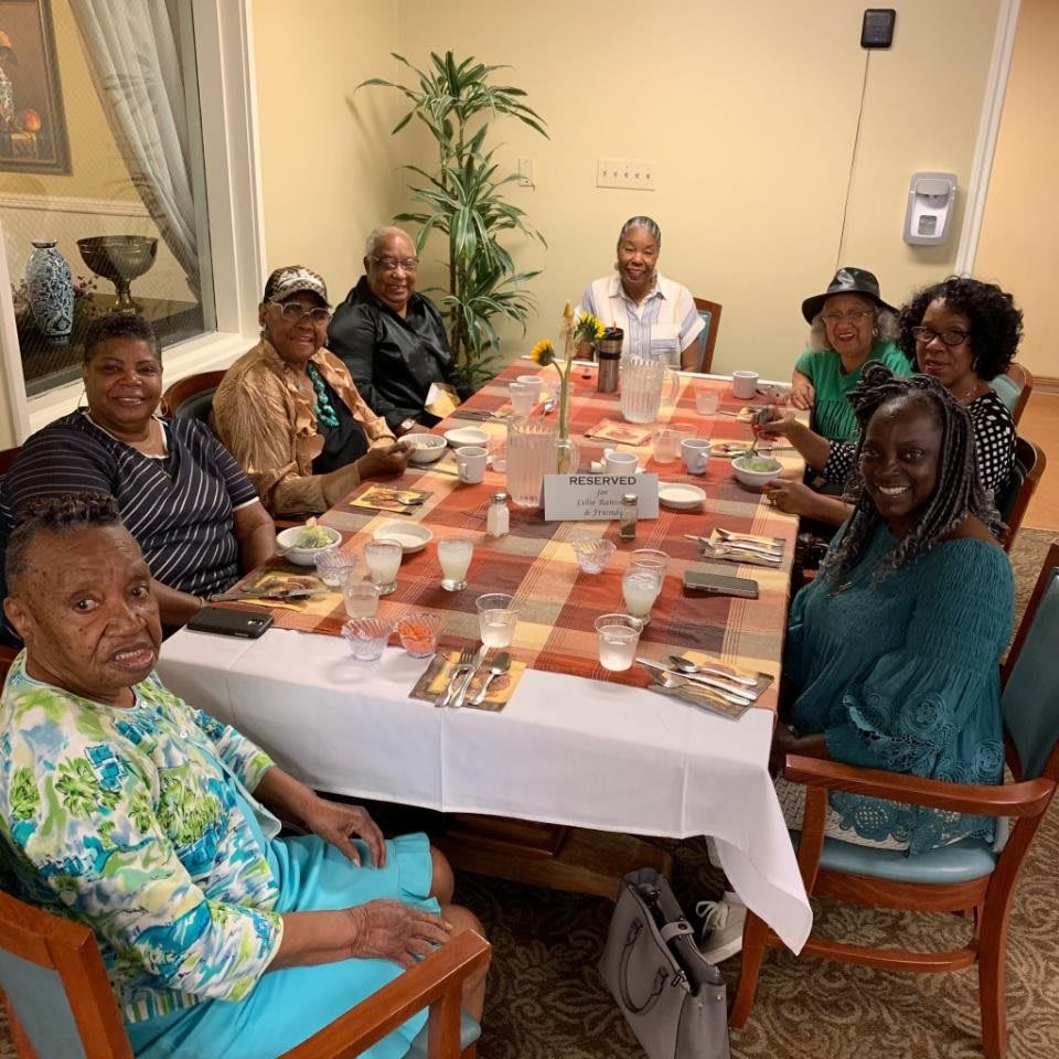 A group of people gathered around a dining table, smiling and enjoying their time together indoors.