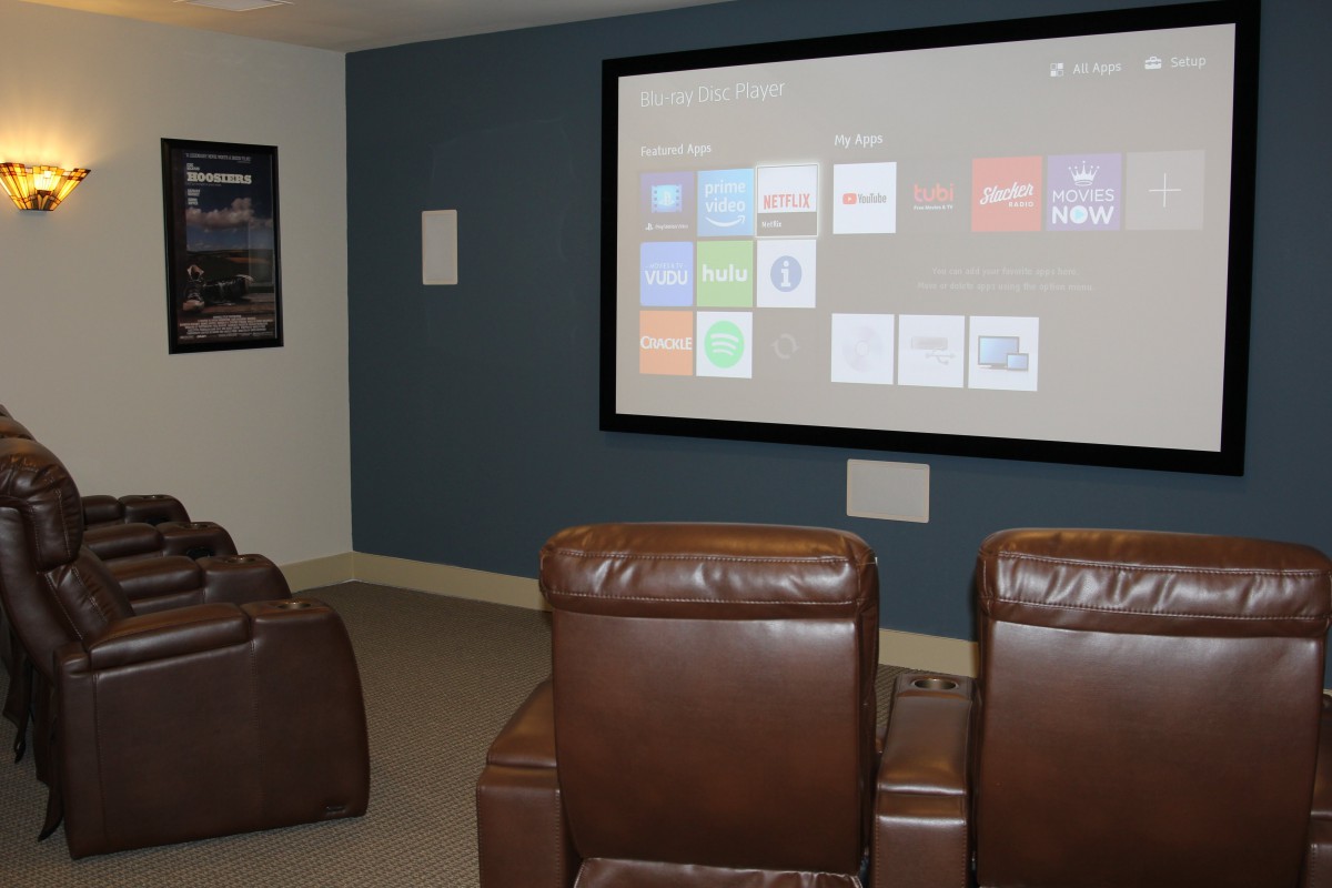 A cozy home theater setup with comfortable chairs facing a large projection screen.