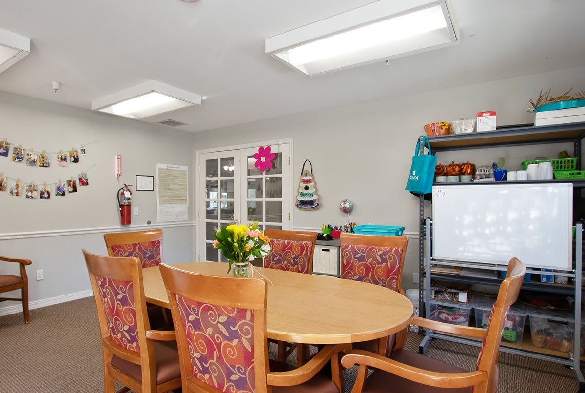A well-lit classroom or meeting room with a large table, colorful chairs, a whiteboard, and decorative elements.