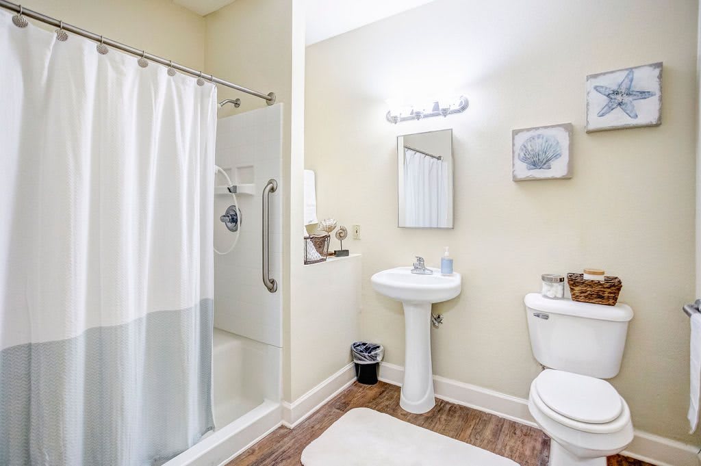 A clean and bright bathroom with a shower, sink, and toilet.