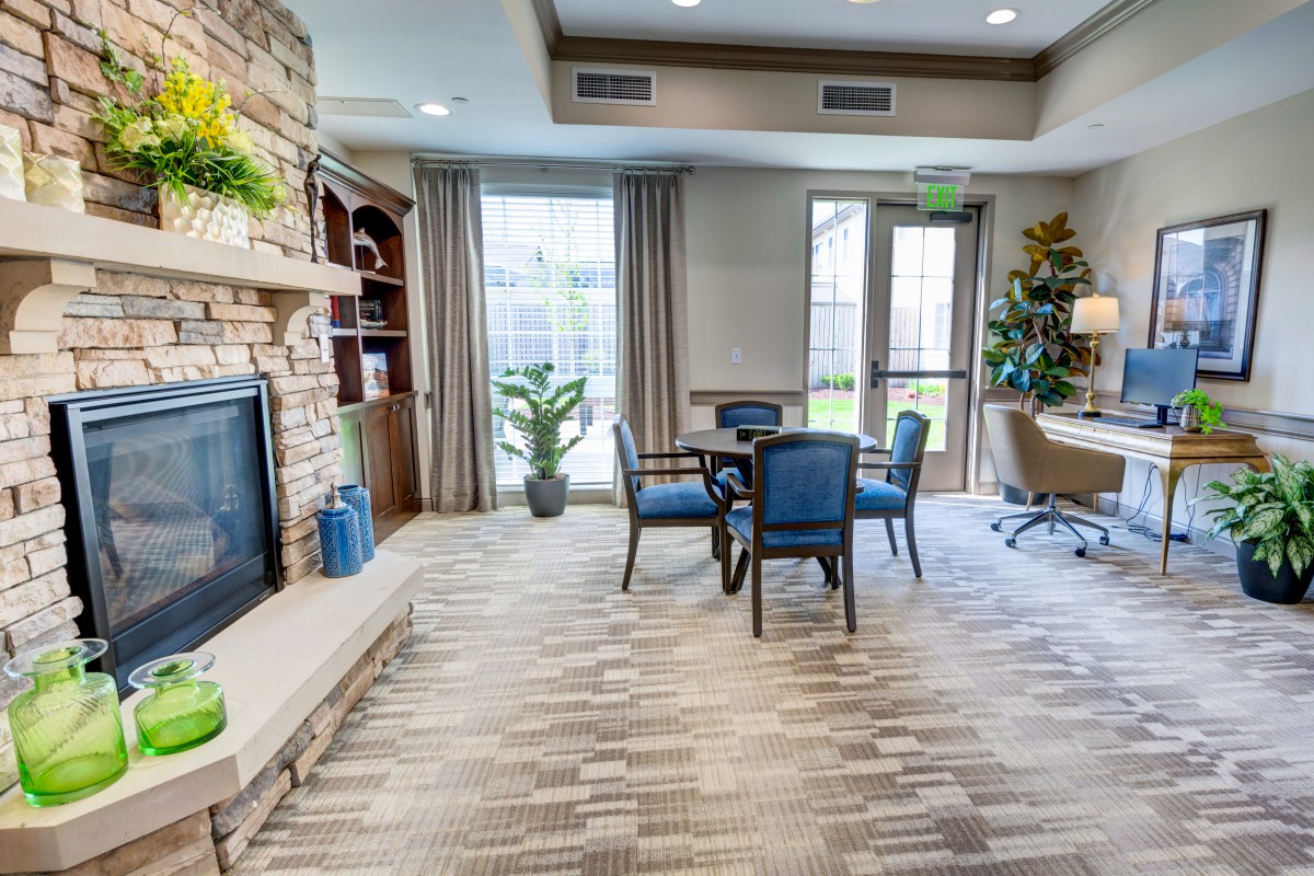 A cozy living room with a fireplace, round table, and comfortable chairs.