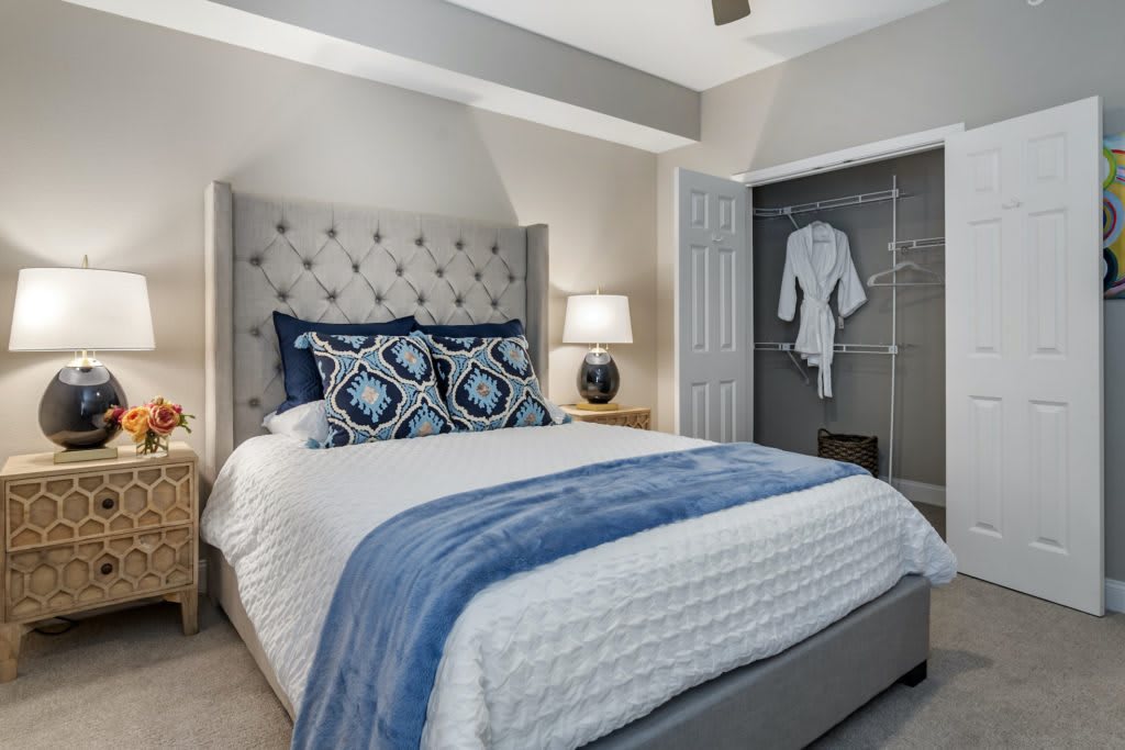 A neatly arranged bedroom with a stylish bed, decorative pillows, and an open closet.