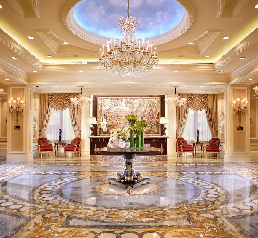 A luxurious hotel lobby with an ornate chandelier and marble flooring.