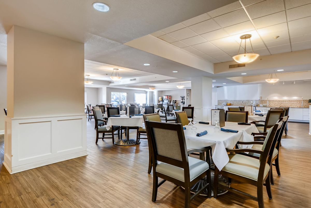 A spacious dining area with elegantly set tables and comfortable chairs, featuring ambient lighting and a polished interior.