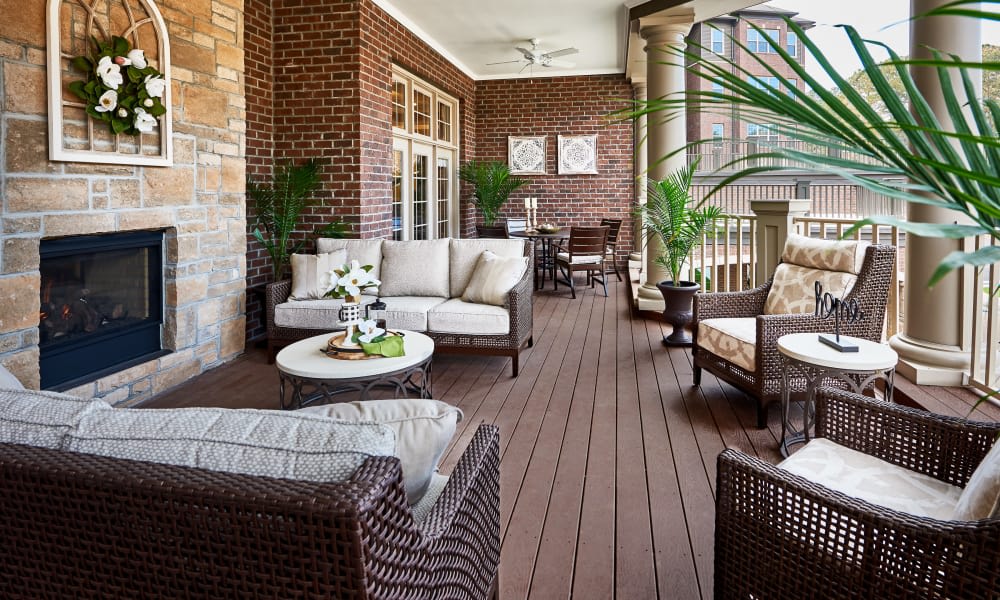 A cozy outdoor patio with wicker furniture and lush green plants.