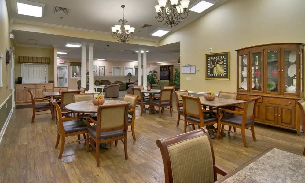 A well-lit dining area with multiple tables and chairs, featuring wooden flooring and decorative artwork.