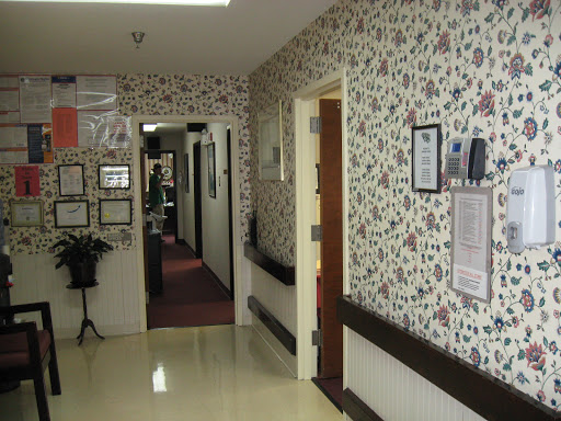A view of a decorated hallway in an office, featuring floral wallpaper and doors leading to different rooms.