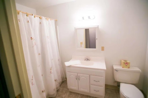 A clean and simple bathroom featuring a white vanity, shower curtain, and modern lighting.