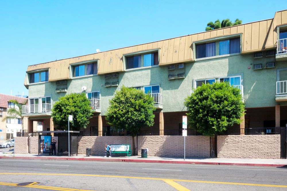 A residential apartment building with trees lining the street in front.