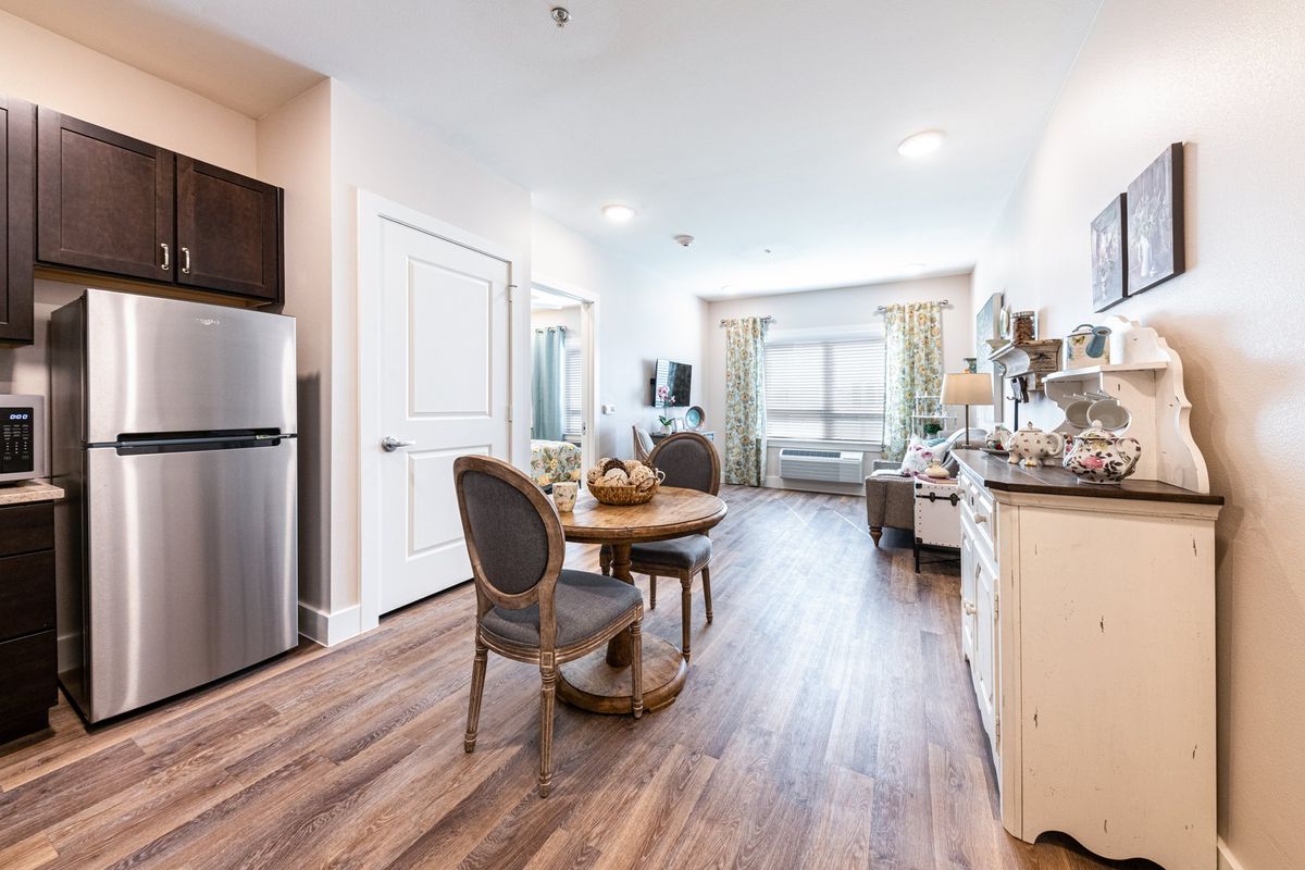 A modern apartment interior with a cozy living and dining area, featuring wood flooring and elegant furnishings.