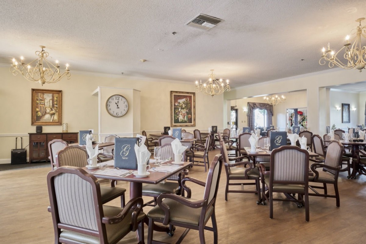 An elegant dining area with neatly arranged tables and chairs under soft lighting.